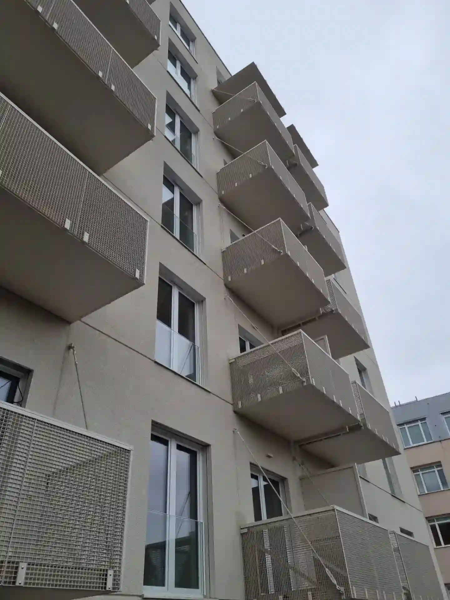 Pohled zdol na závěsné balkóny s těhokovovými výpl
