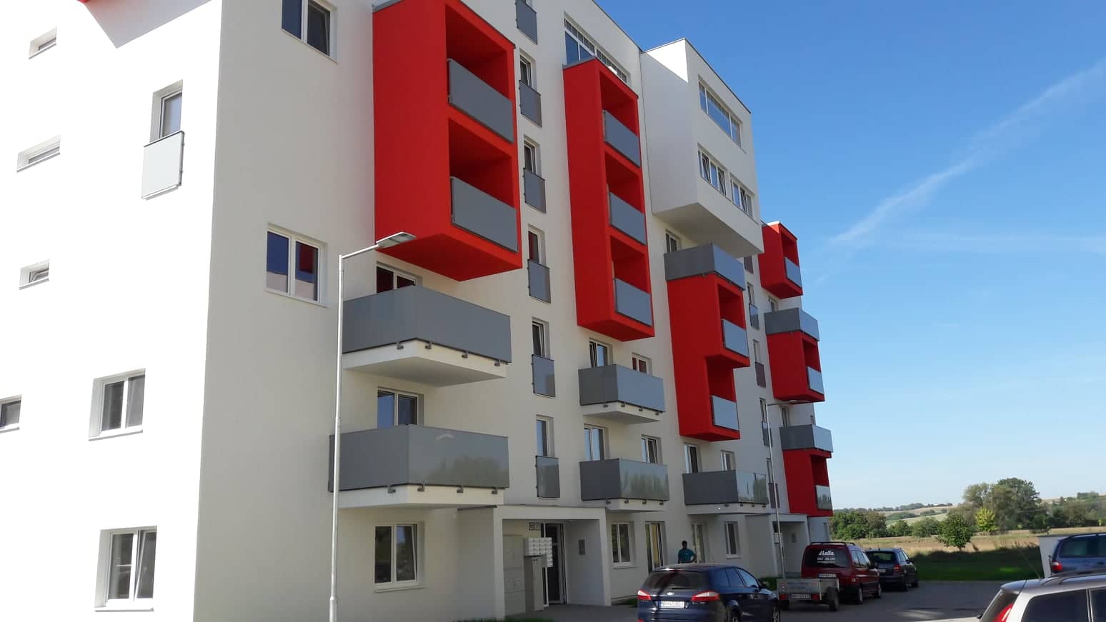 Bytový dům ve Vráblech s červenými předsazenými balkony KOVERON
