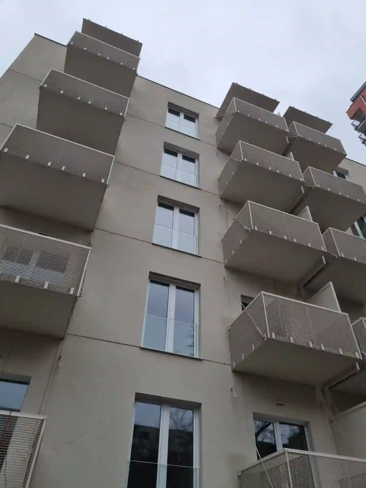 Dvě řady balkonů s těhokovovým zábradlím na světlé fasádě