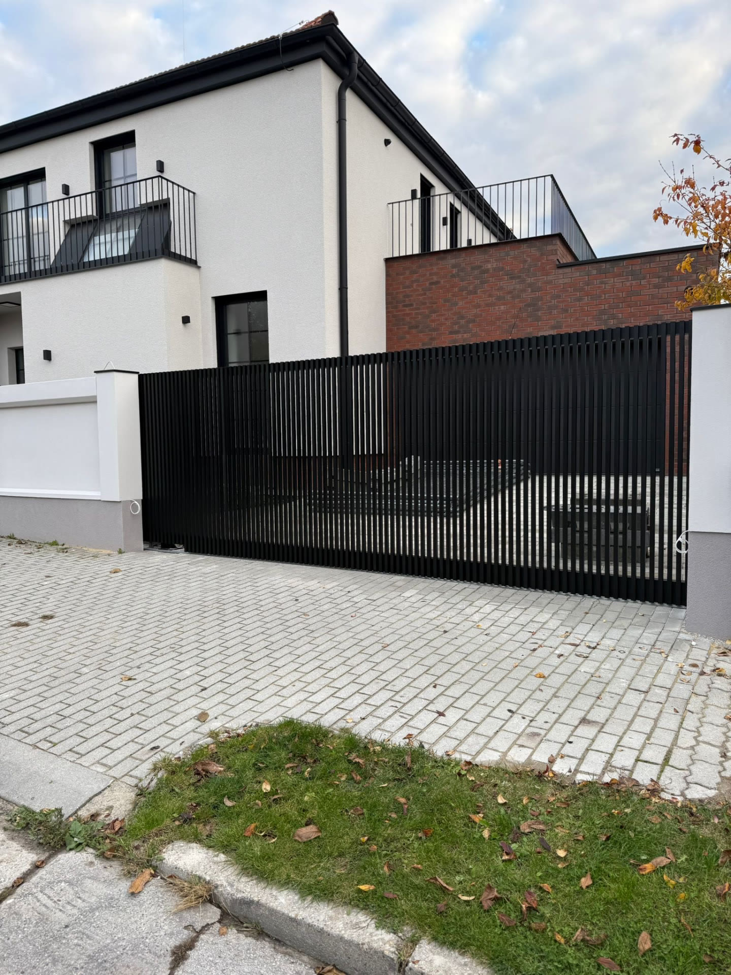 Černé lamelové oplocení s posuvnou bránou u dlažbového vjezdu