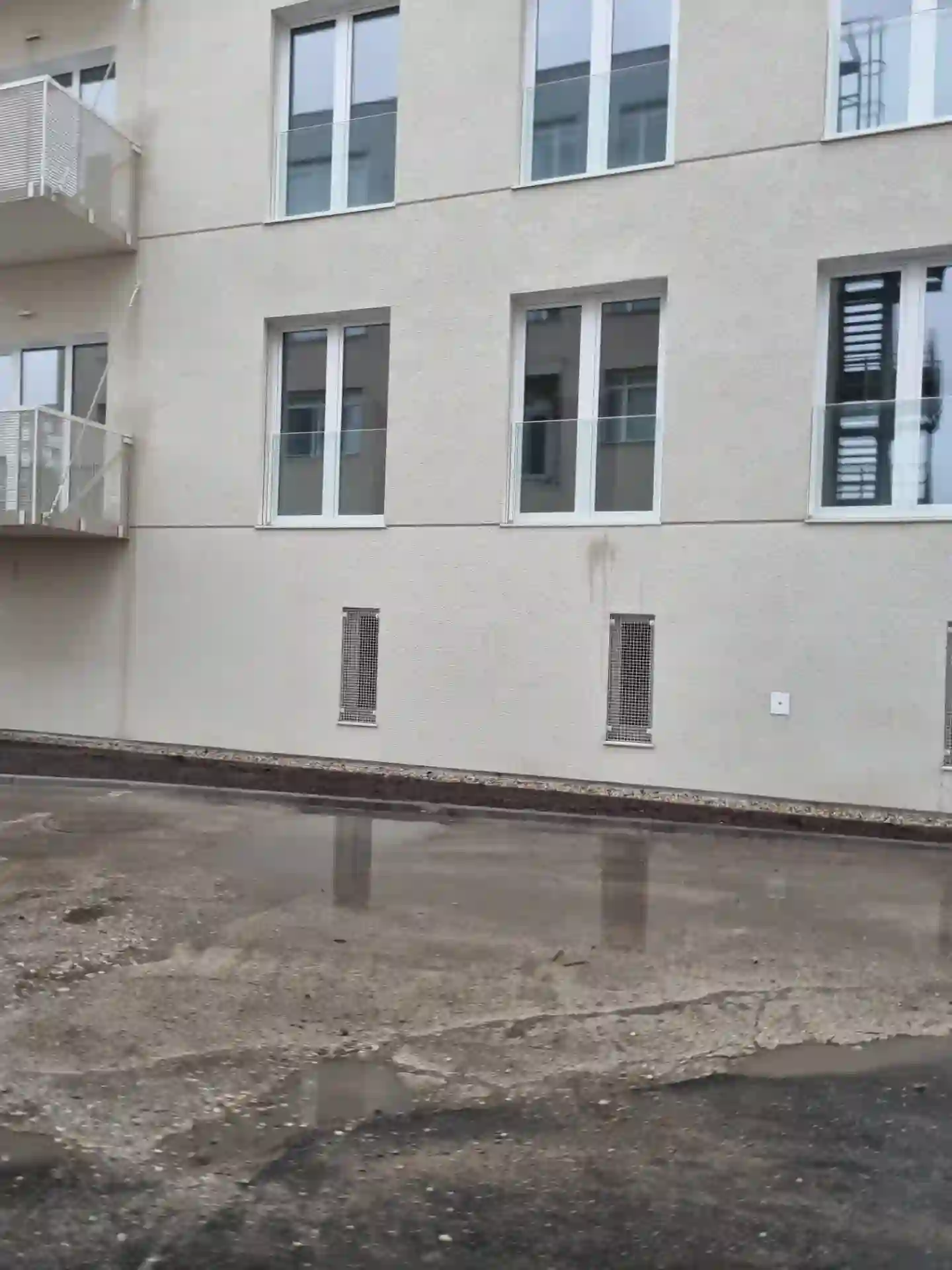 Dokončená fasáda bytového domu s balkony a větrací mříž